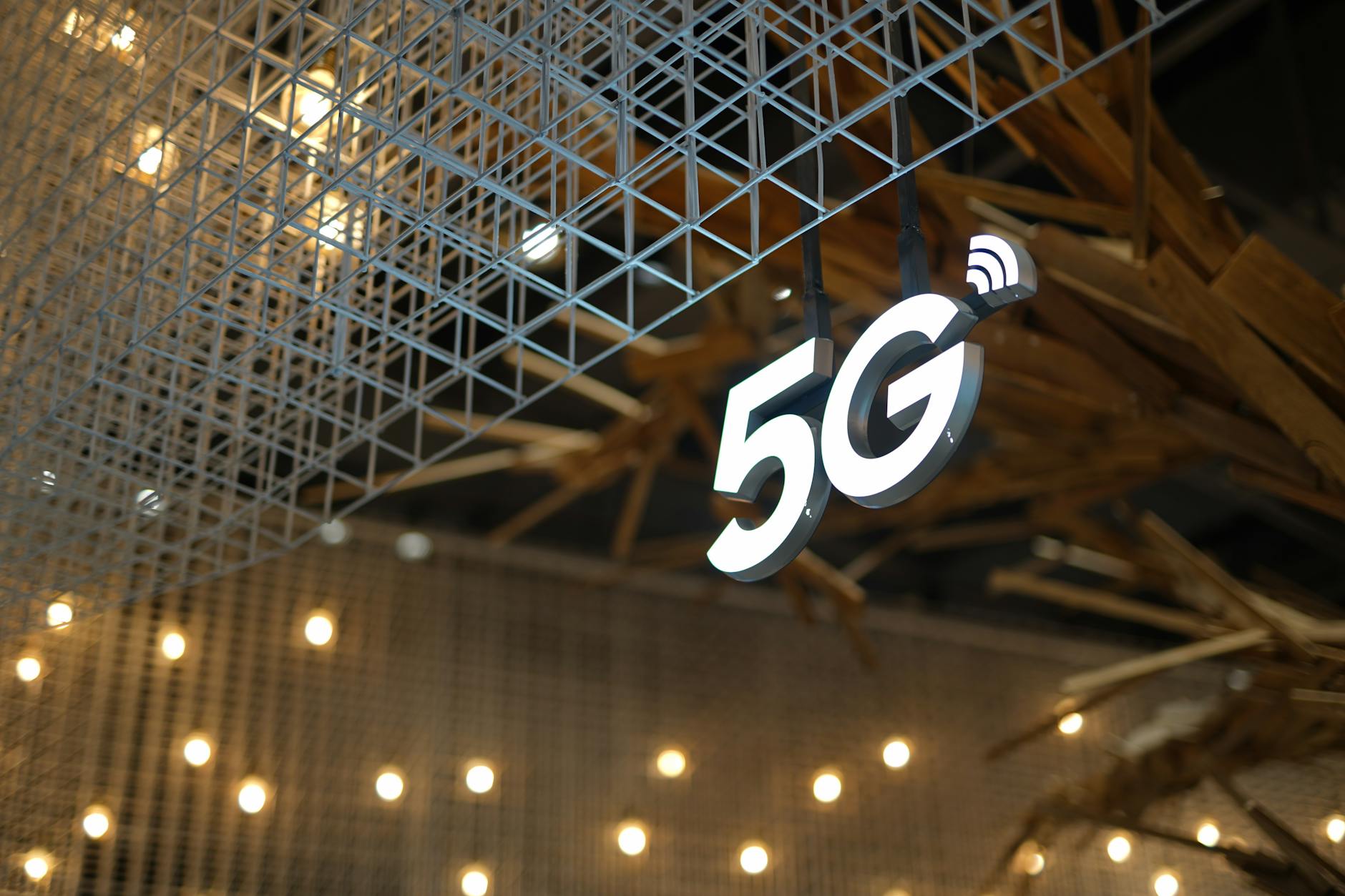 Czy 5G zastąpi firmowe łącza kablowe? Analiza kosztów, ryzyk i wydajności dla biznesu Podświetlony napis 5G na tle nowoczesnego sufitu w ciepłym świetle