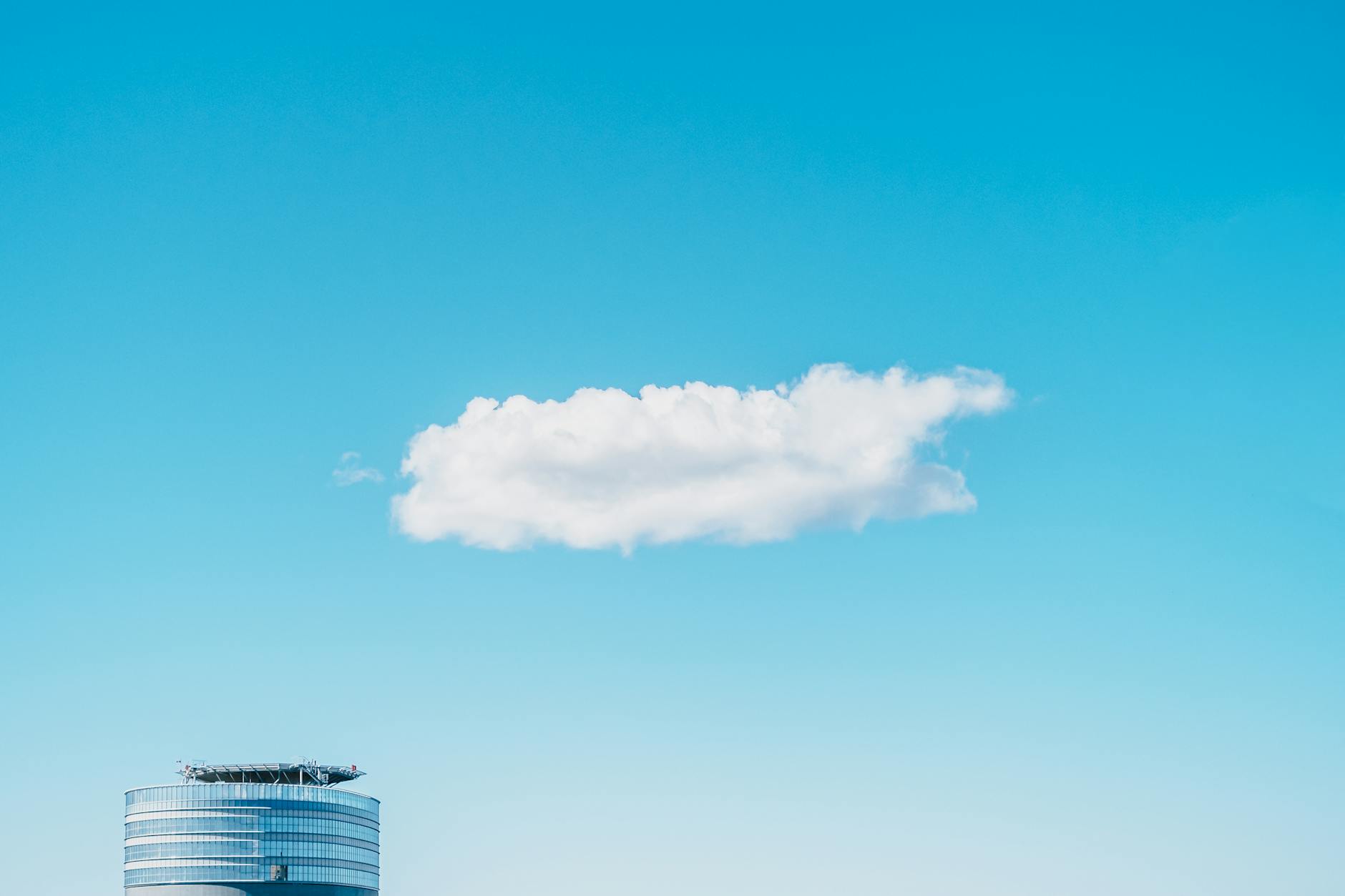 Chmura nad szklanym wieżowcem symbolizująca hybrydową infrastrukturę AI