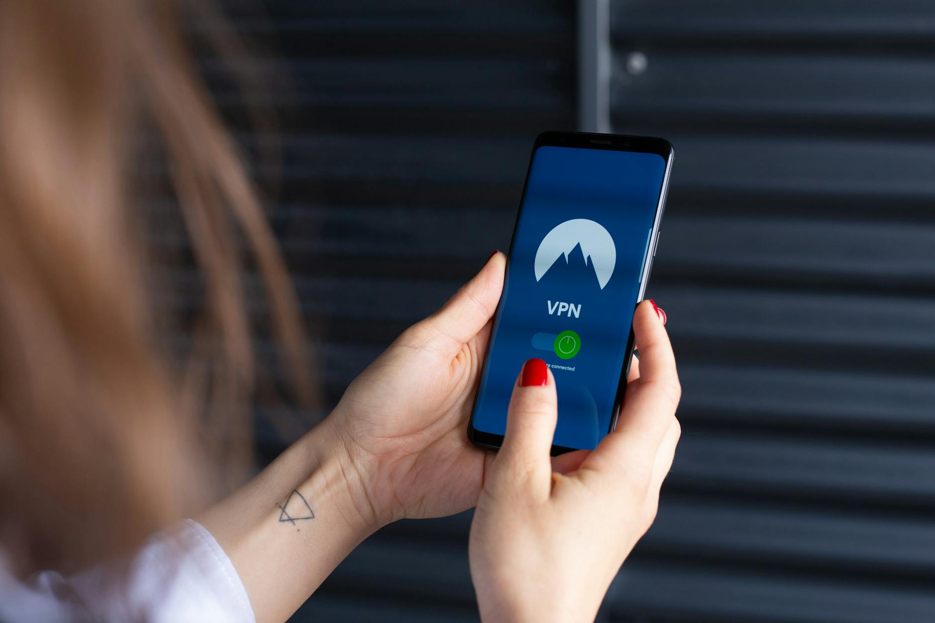 Dłonie kobiety uruchamiające aplikację VPN na smartfonie